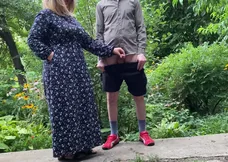 A senior lady helps her stepson pee outside and participates by standing